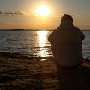 Pessoa sentada pensativa, com cores suaves ao redor, simbolizando a busca por alívio da ansiedade e depressão.