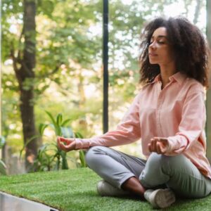 Pessoa meditando em um ambiente tranquilo com luz natural, simbolizando estratégias de autocuidado e bem-estar mental e a prática de meditação e mindfulness.