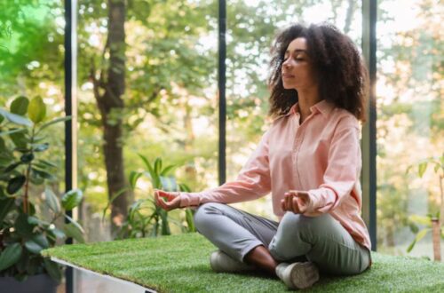 Pessoa meditando em um ambiente tranquilo com luz natural, simbolizando estratégias de autocuidado e bem-estar mental e a prática de meditação e mindfulness.