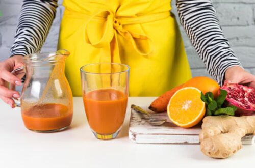 Copo de vitamina colorida com frutas frescas ao redor, em um ambiente saudável.